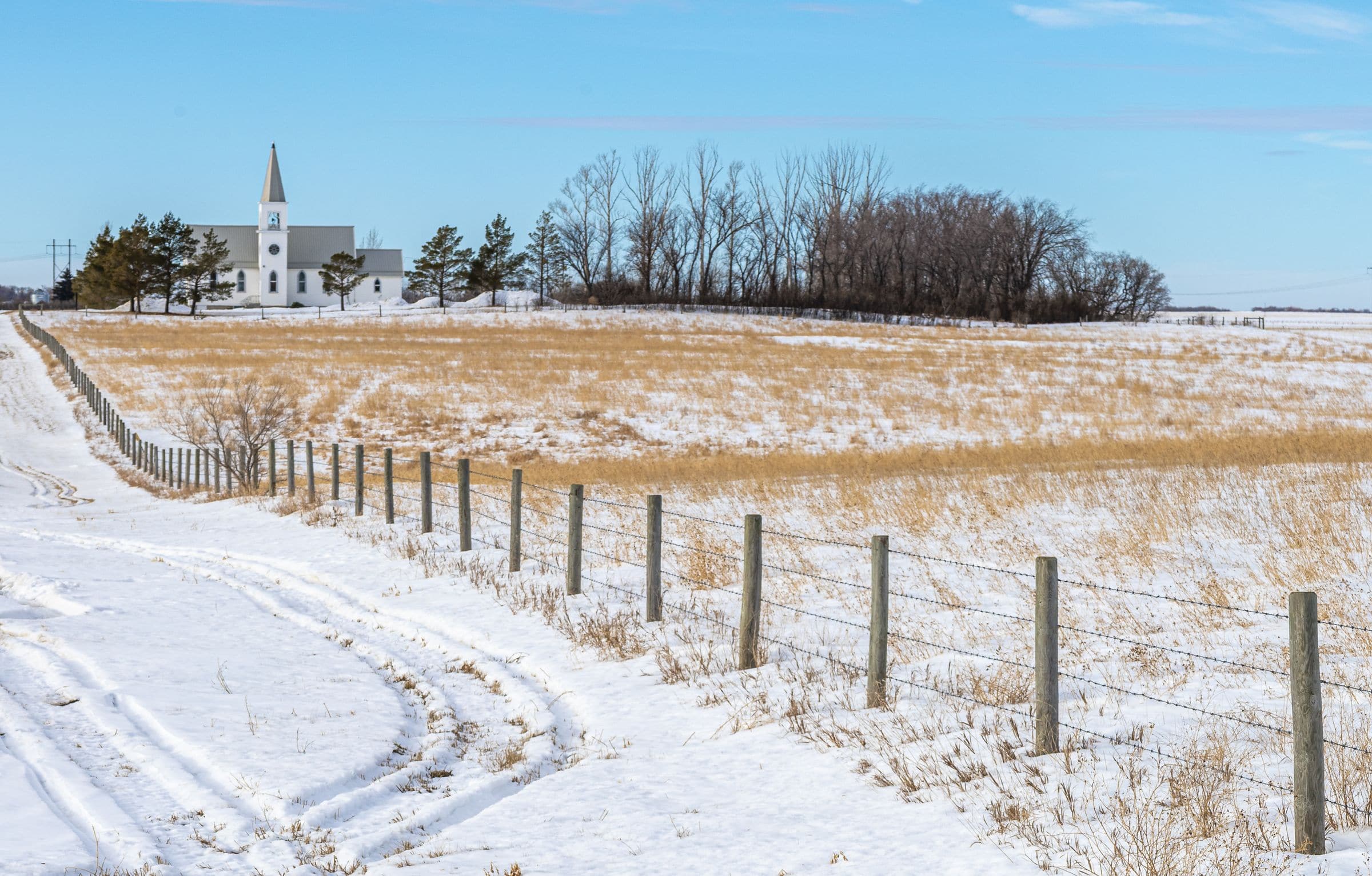 Windshield replacement Dalmeny area: white country church and barbed wire fence beside a snowy prairie field