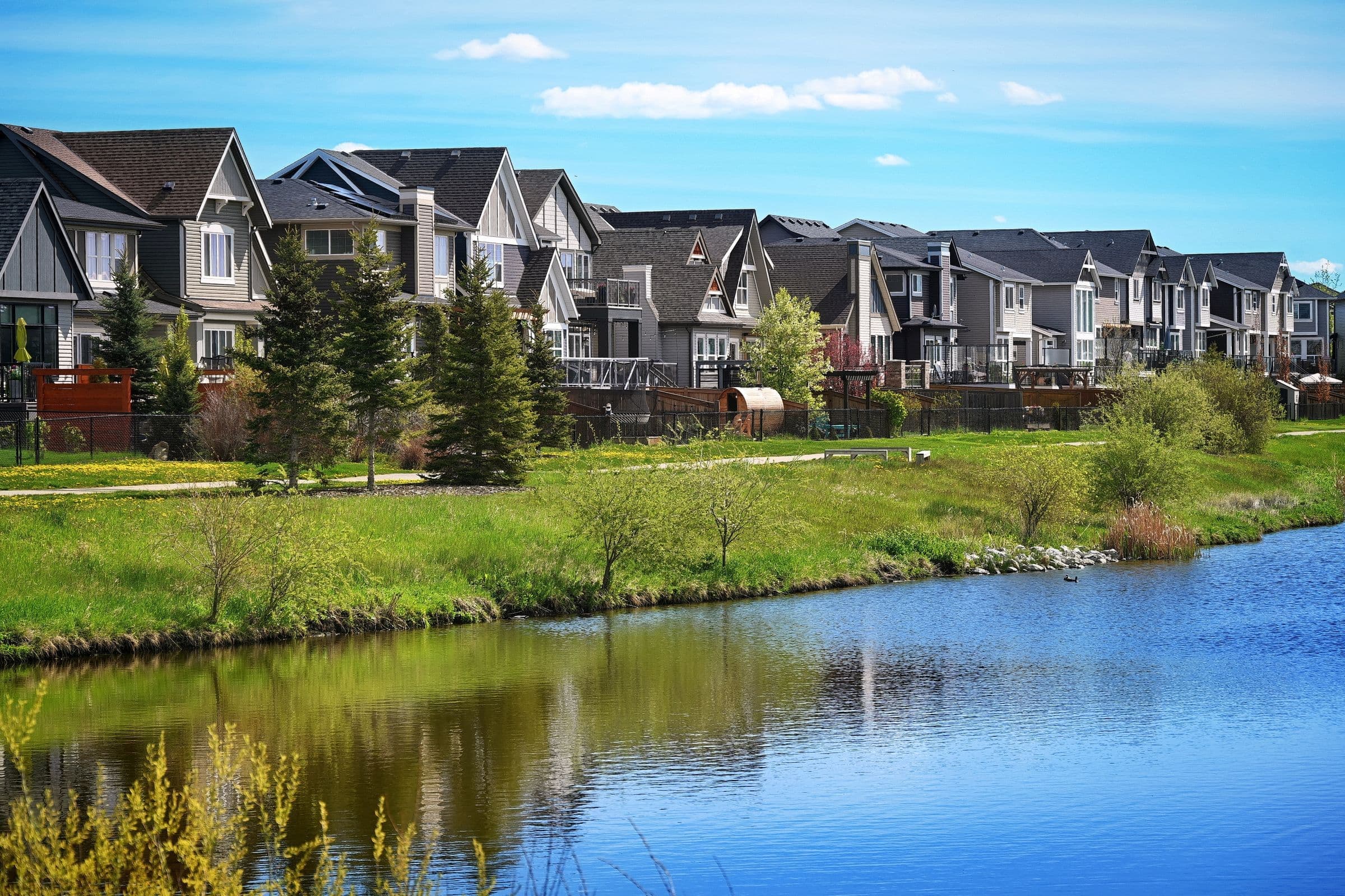 Windshield replacement Martensville area: row of newer two-storey houses along a storm pond in a prairie suburb